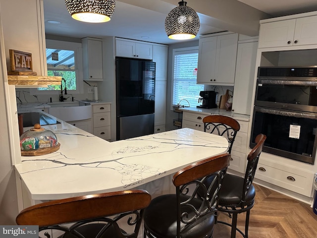 kitchen featuring a kitchen bar, double wall oven, refrigerator with glass door, and a wealth of natural light