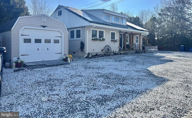 view of front of home with an outbuilding, an attached garage, covered porch, and driveway