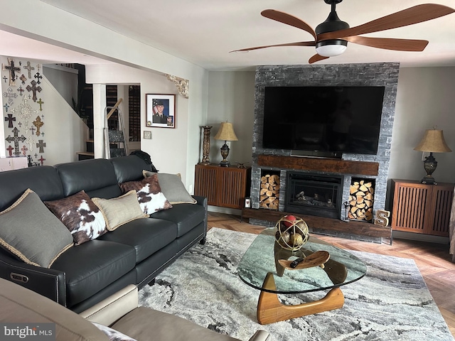 living area with a stone fireplace and ceiling fan