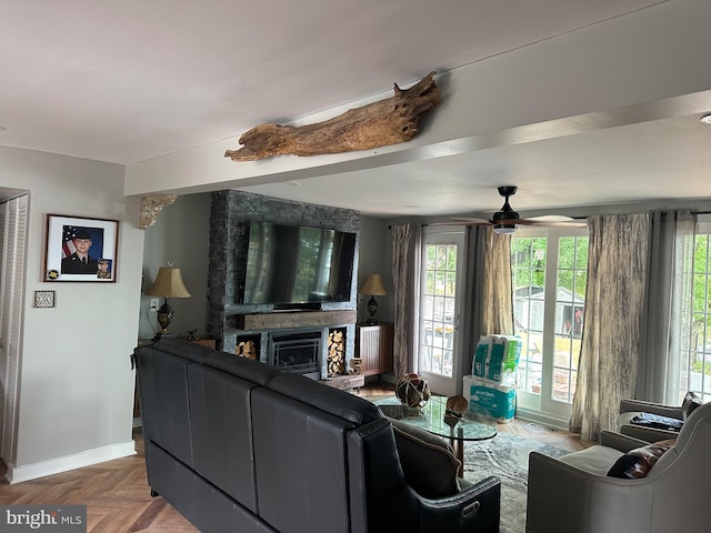 living room with a fireplace, a ceiling fan, and baseboards