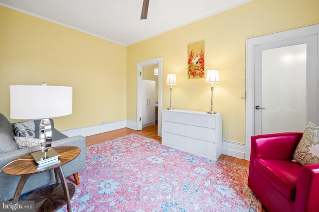 sitting room featuring ornamental molding, baseboards, and wood finished floors