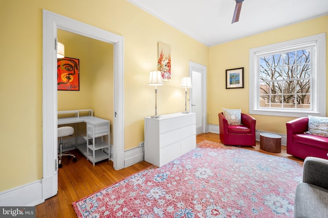 sitting room with ceiling fan, hardwood / wood-style flooring, and baseboards