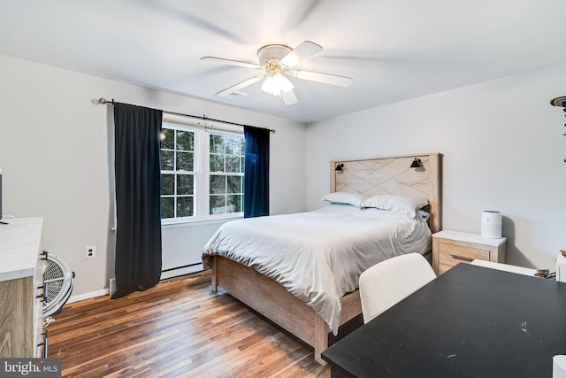 bedroom with wood-type flooring, visible vents, a baseboard heating unit, a ceiling fan, and baseboards