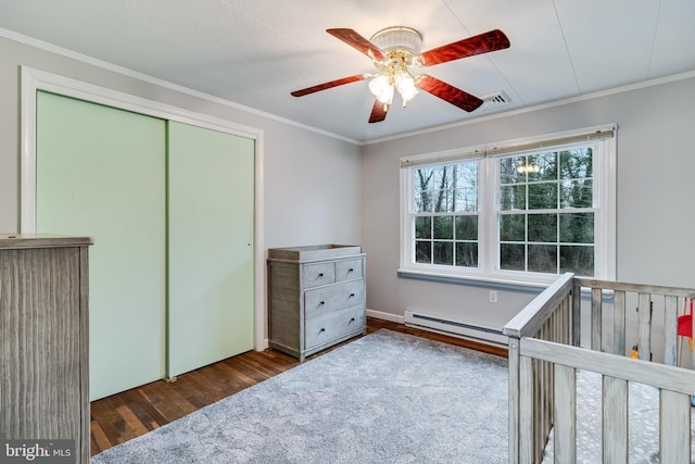 bedroom with a baseboard radiator, wood finished floors, ornamental molding, a closet, and a nursery area