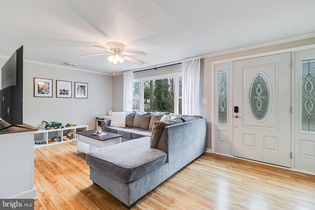 living room featuring ornamental molding, ceiling fan, light wood finished floors, and visible vents