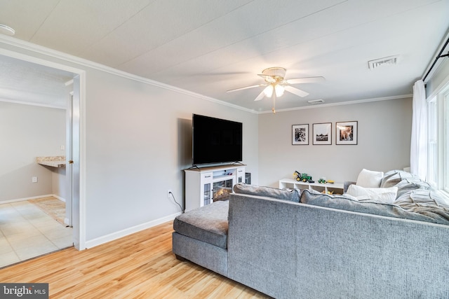 living room featuring baseboards, visible vents, ceiling fan, crown molding, and light wood-type flooring