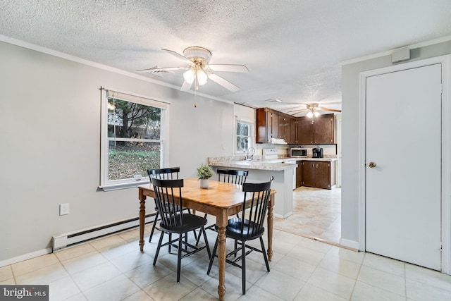 dining space with a baseboard heating unit, ornamental molding, a ceiling fan, a textured ceiling, and baseboards