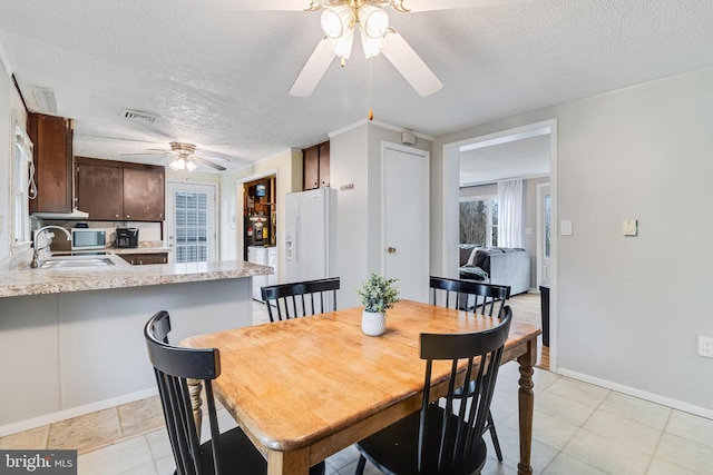 dining space with light tile patterned floors, visible vents, ceiling fan, a textured ceiling, and baseboards