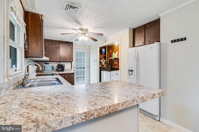 kitchen with light countertops, visible vents, a sink, separate washer and dryer, and white fridge with ice dispenser