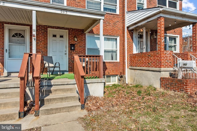 view of exterior entry featuring covered porch and brick siding