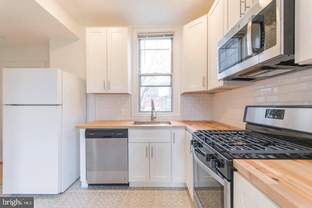 kitchen featuring a sink, wood counters, white cabinetry, appliances with stainless steel finishes, and decorative backsplash