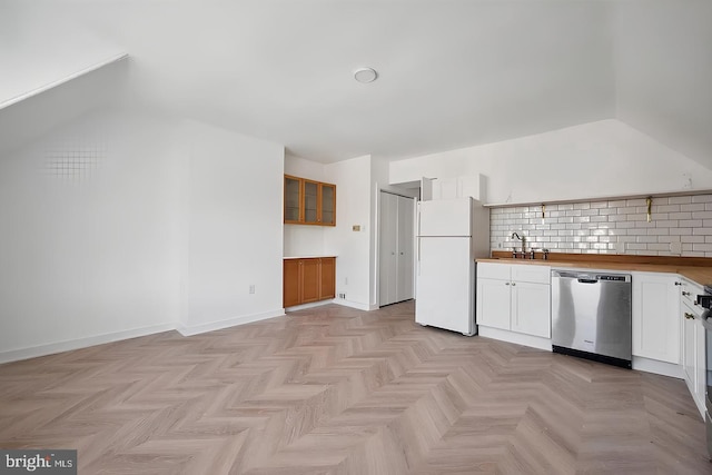 kitchen with tasteful backsplash, dishwasher, freestanding refrigerator, white cabinetry, and a sink