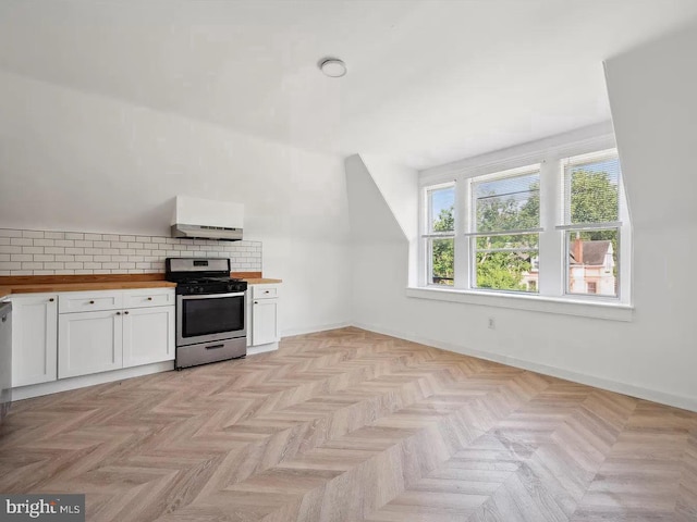 kitchen with butcher block countertops, white cabinetry, baseboards, stainless steel gas stove, and tasteful backsplash