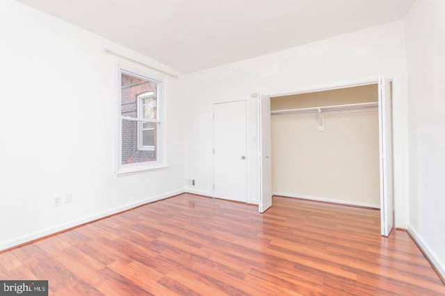 unfurnished bedroom with a closet, wood finished floors, and baseboards