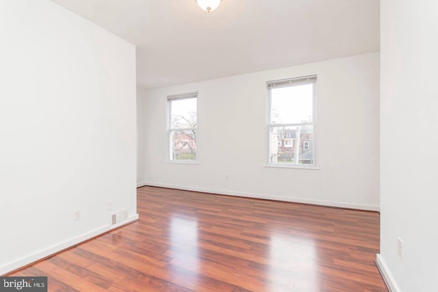 unfurnished room with visible vents, baseboards, and wood finished floors