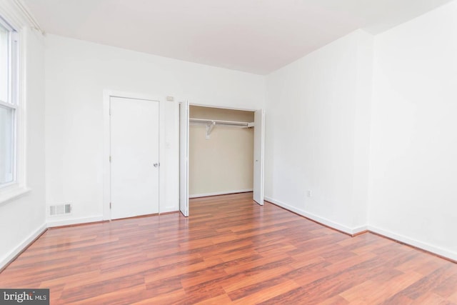 unfurnished bedroom with visible vents, baseboards, and wood finished floors