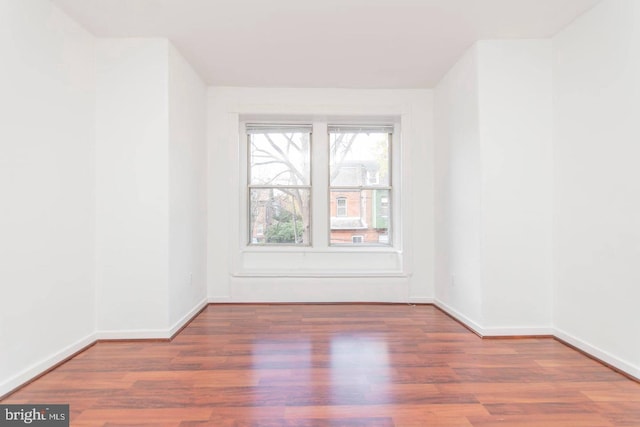 spare room with baseboards and wood finished floors