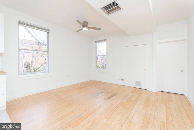 unfurnished room featuring light wood-style floors, ceiling fan, visible vents, and baseboards