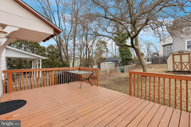 wooden terrace featuring a fenced backyard, an outdoor structure, and a storage unit