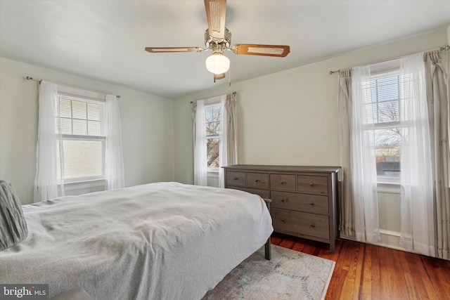 bedroom with a ceiling fan, multiple windows, and wood finished floors