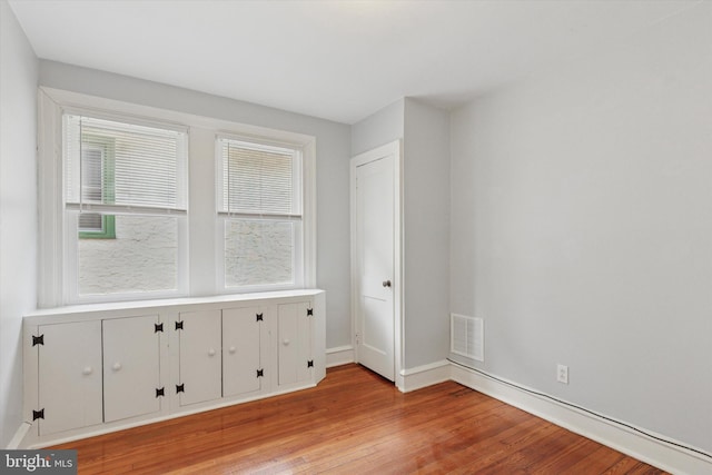 spare room featuring light wood-style flooring, visible vents, and baseboards