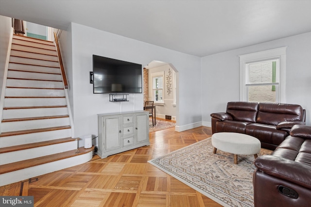 living room with stairway, plenty of natural light, and arched walkways