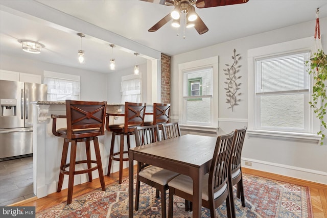 dining room featuring baseboards, a ceiling fan, and light wood-style floors