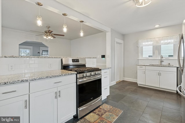 kitchen with a wealth of natural light, backsplash, a sink, and stainless steel gas range oven