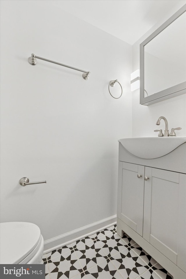 half bathroom featuring vanity, baseboards, and tile patterned floors