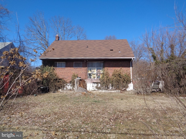 back of property featuring a chimney and brick siding