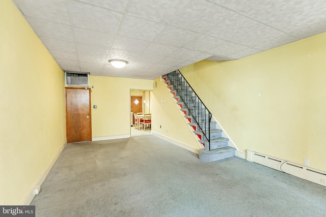 finished basement featuring a baseboard radiator, carpet flooring, stairway, and baseboards