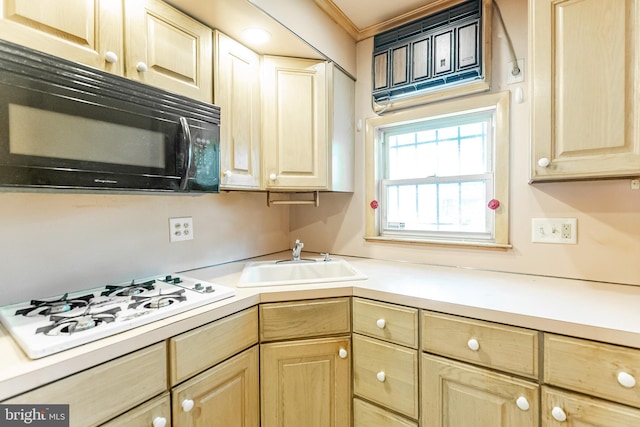 kitchen with black microwave, white gas cooktop, a sink, and light brown cabinetry