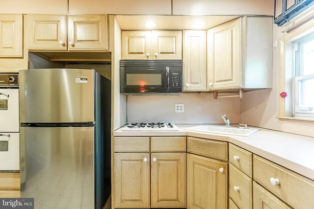 kitchen featuring light countertops, white appliances, light brown cabinets, and a sink