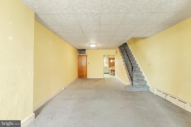 finished below grade area with baseboards, carpet flooring, stairway, and baseboard heating