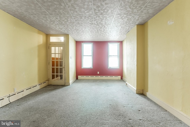 carpeted spare room with a baseboard heating unit, baseboards, and baseboard heating