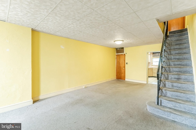 below grade area with stairs, baseboards, and carpet flooring