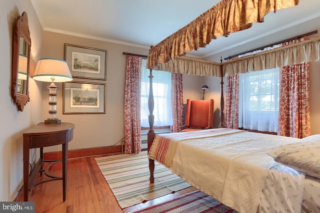 bedroom featuring baseboards, crown molding, and wood finished floors