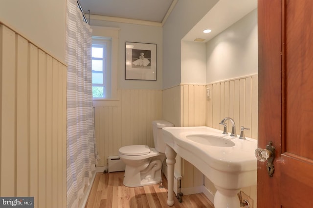 bathroom featuring a baseboard radiator, toilet, ornamental molding, wainscoting, and wood finished floors