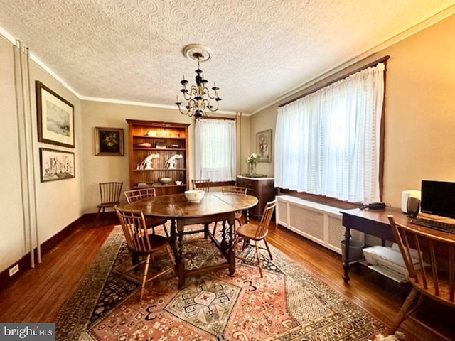 dining room featuring a textured ceiling, a notable chandelier, wood finished floors, ornamental molding, and radiator