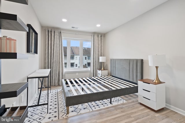 bedroom with baseboards, wood finished floors, visible vents, and recessed lighting