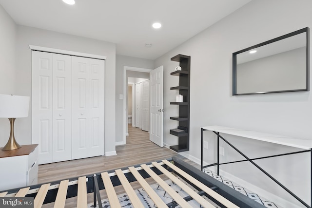 unfurnished bedroom featuring light wood-style flooring, baseboards, a closet, and recessed lighting