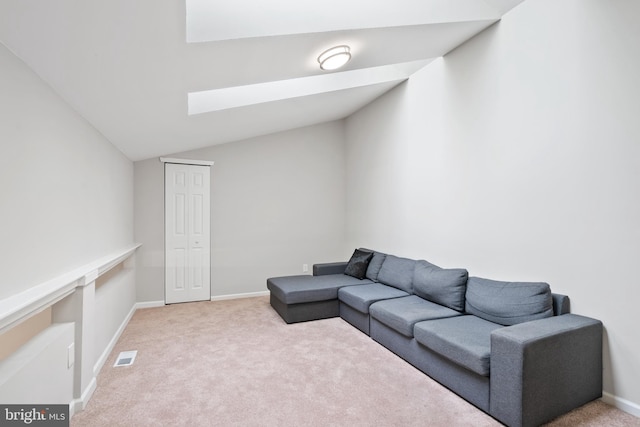 carpeted living area featuring lofted ceiling with skylight, visible vents, and baseboards