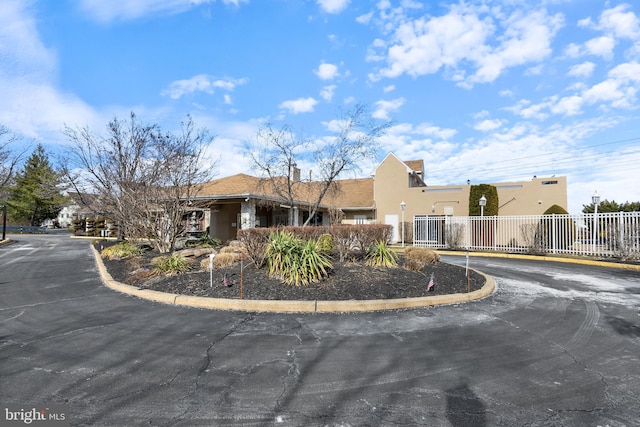 view of front of property featuring a gate, driveway, fence, and stucco siding