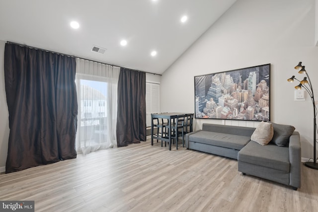 living area with high vaulted ceiling, wood finished floors, visible vents, and recessed lighting