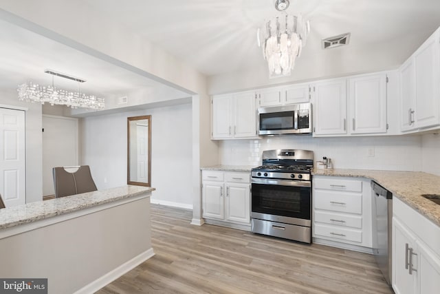 kitchen with decorative backsplash, light wood-style flooring, light stone counters, stainless steel appliances, and white cabinetry