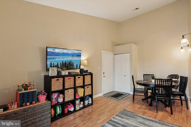 dining room with a towering ceiling, baseboards, and wood finished floors