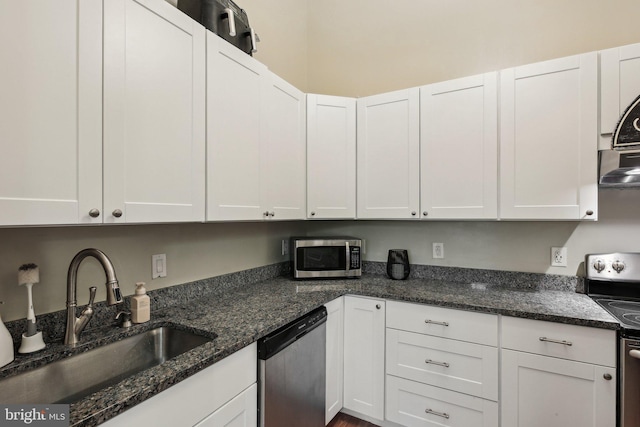 kitchen featuring dark stone countertops, white cabinetry, stainless steel appliances, and a sink