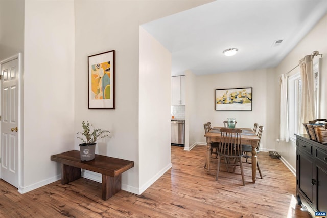 dining room featuring light wood-type flooring, visible vents, and baseboards