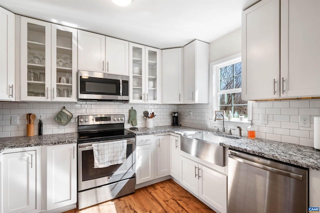 kitchen with stainless steel appliances, light wood-type flooring, white cabinetry, and a sink