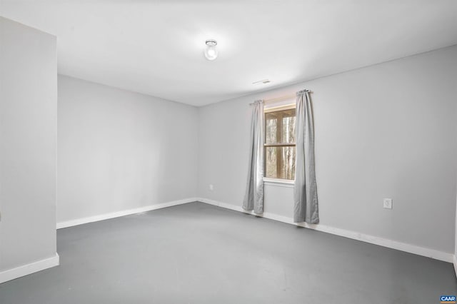 empty room featuring concrete flooring, visible vents, and baseboards